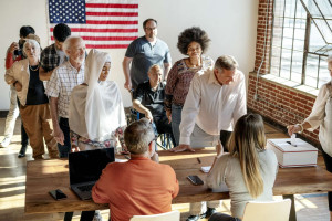 Americans waiting in line to vote with American flag on the wall