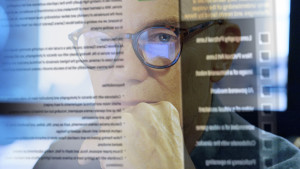 Superimposed image of man with glasses looking at screen and text on screen