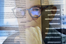 Superimposed image of man with glasses looking at screen and text on screen