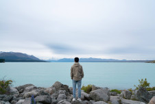 Man standing in front of a vast lake and sky