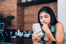 Young adult looking at her smartphone with depressed look on her face