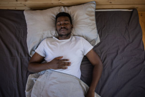 Looking down on a man sleeping in bed, with his hand on his chest