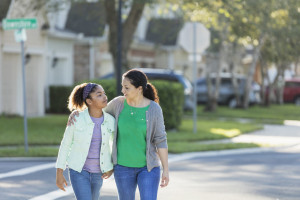 Mother with her arm around her daughter, walking in the street and talking