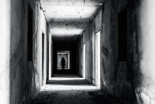 A dirty, creepy hallway with the silhouette of a person at the end