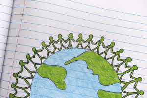 Illustration of people holding  hands standing around the sides of the globe on lined paper