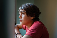 Teen boy looking pensively out a window