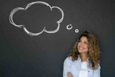 Woman smiling up at memory cloud on blackboard behind her