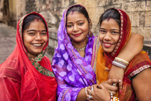 Three women smiling in Jodhpur, India, with their arms around each other