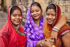 Three women smiling in Jodhpur, India, with their arms around each other