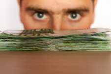 Man staring over a pile of money