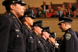 Assistant Chief of Police Paul Figueroa, center, congratulates graduates after they are presented with their badges during the graduation ceremony for the 167th Police Academy at the Scottish Rite Temple in Oakland, California