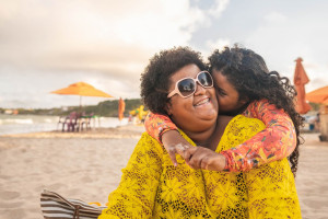 Daughter hugging and kissing her mother on the beach