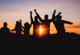 Group of people celebrating with sunset behind them