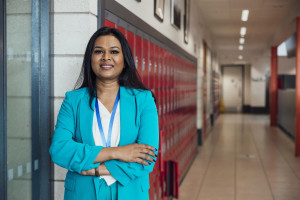 Principal standing in a school hallway in front of lockers with arms crossed on her chest