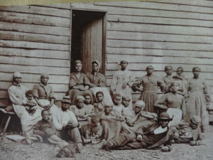 A group of 22 slaves posing in front of a building