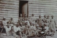 A group of 22 slaves posing in front of a building