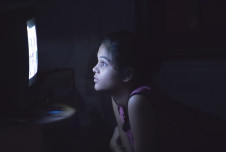 Pensive child staring at TV screen