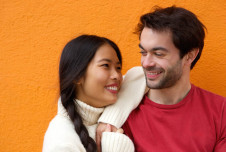 Couple standing together looking at each other, with her elbow on his shoulder