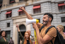 Man with a microphone and fist raised at a protest