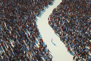 Single person walking through the path between two huge crowds of people