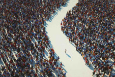 Single person walking through the path between two huge crowds of people