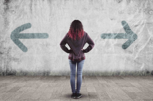 Woman stands in front of a wall with arrows pointed in opposite directions