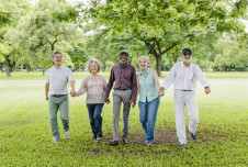 Five friends holding hands walking in a park