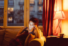 Woman sitting on her couch in the evening looking at her phone