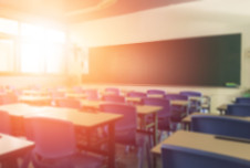 An empty modern classroom aglow from the afternoon sun peeking through its windows.