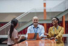 Three teachers sitting at a table talking and smiling