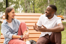 Two friends sitting on park bench talking