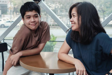 A mother and her teenage son are sitting at a table, sharing a moment of connection