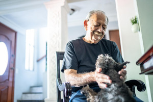 Old man sitting in a chair smiling down at a dog who has its paws in his lap