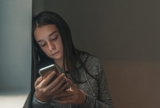 a girl using her phone in a little dark room alone