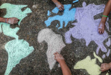 Chalk-drawn map of the globe with hands holding chalk over it