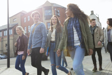 A group of young adults walking together in an urban area, smiling and chatting
