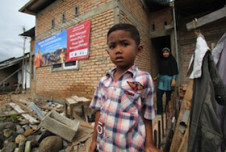 A boy stands outside his home following the devastating 2009  earthquake in Padang, Indonesia. 