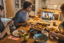 Family having a Thanksgiving meal while video chatting with a loved one on a laptop